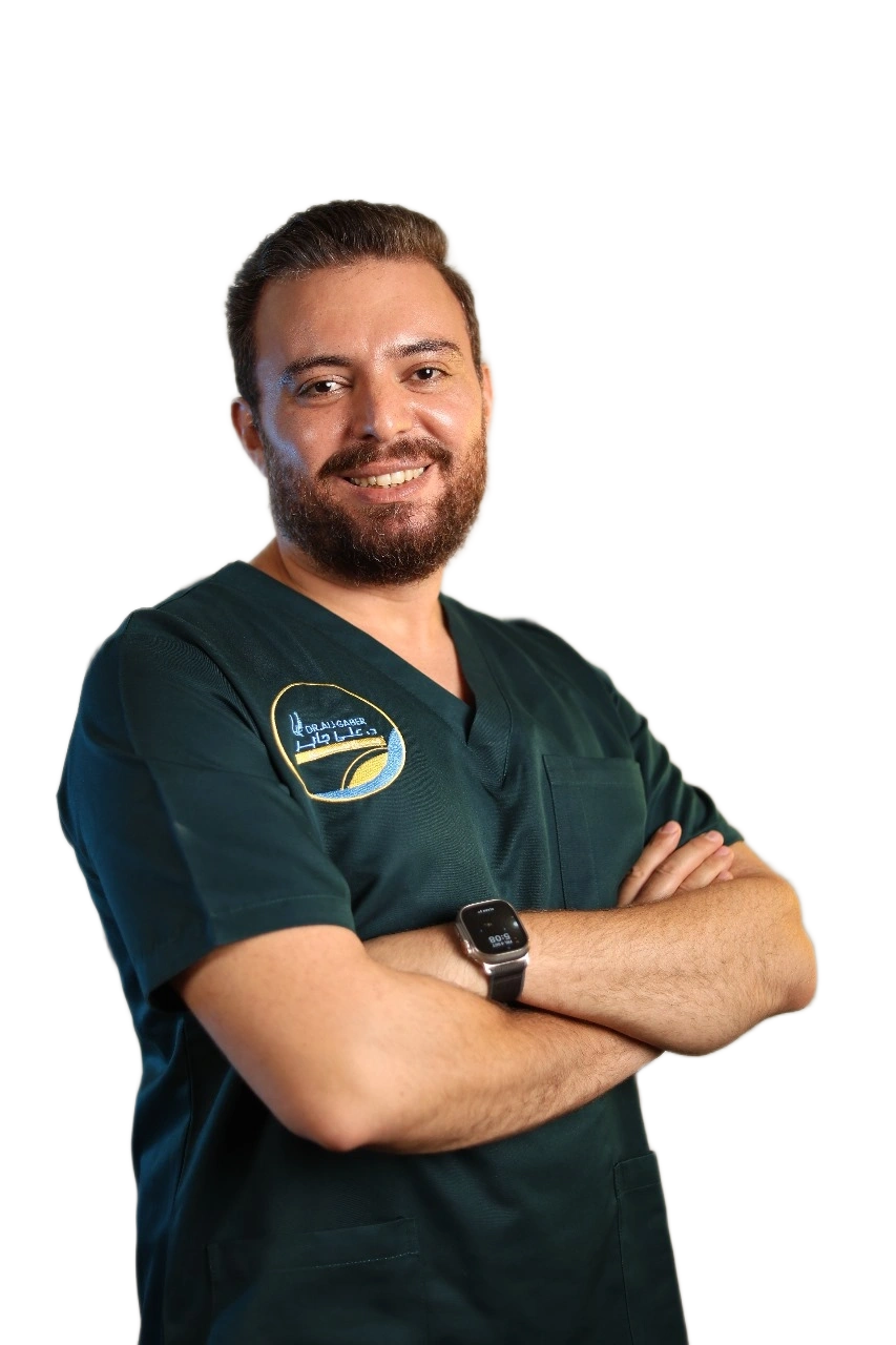 Smiling Dr. Ali Gaber in green scrubs with arms crossed posing.